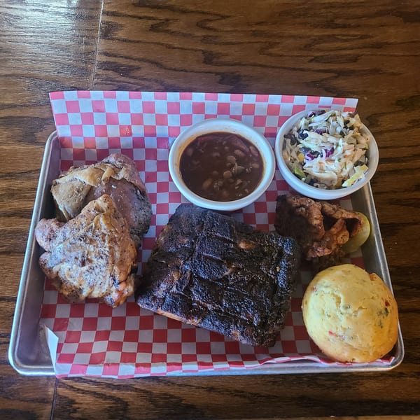 Longhorn Outpost & Barbeque Company's BBQ platter with ribs, chicken, baked beans, coleslaw, and cornbread.